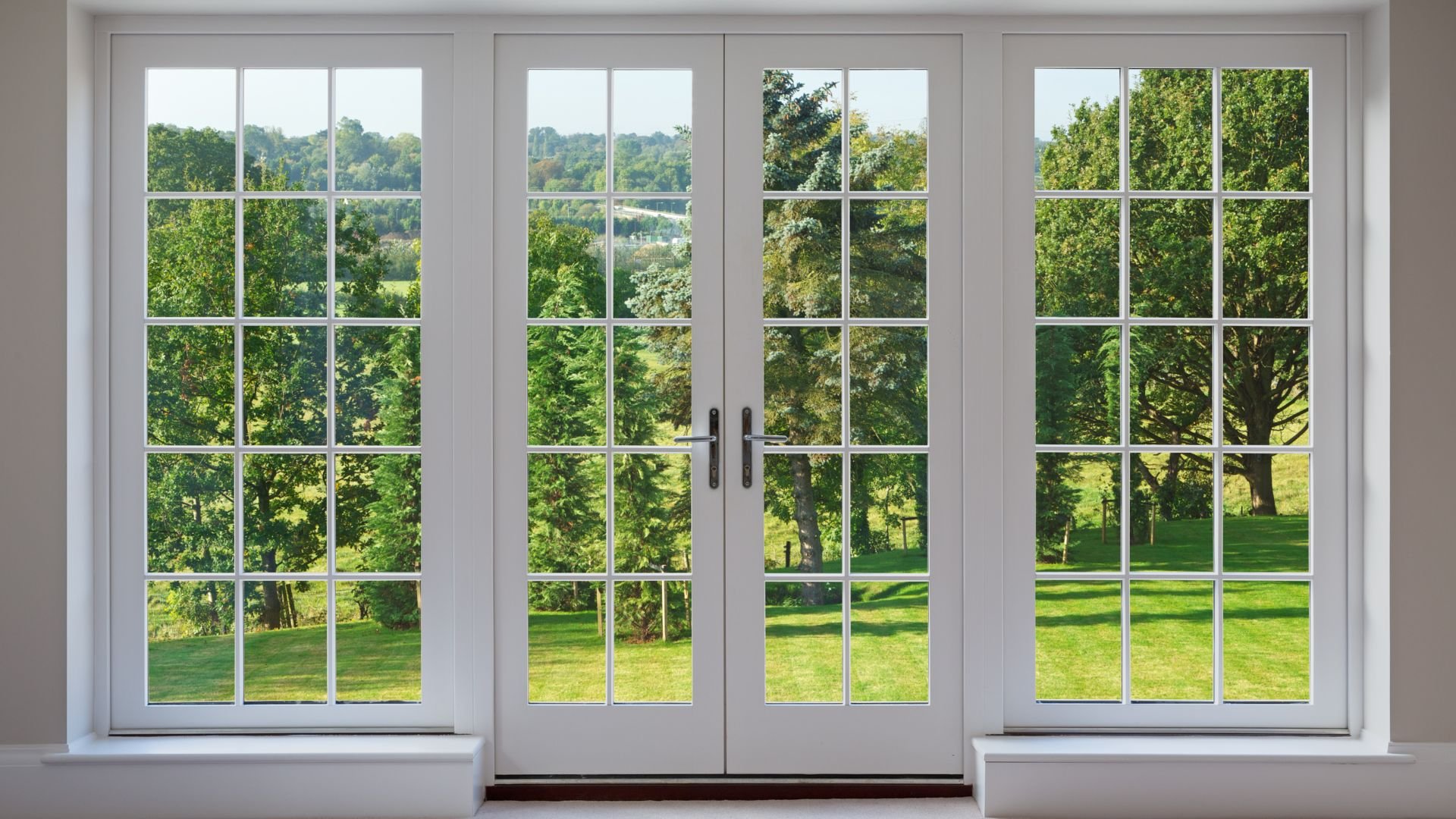 White french doors open to lush green garden and trees