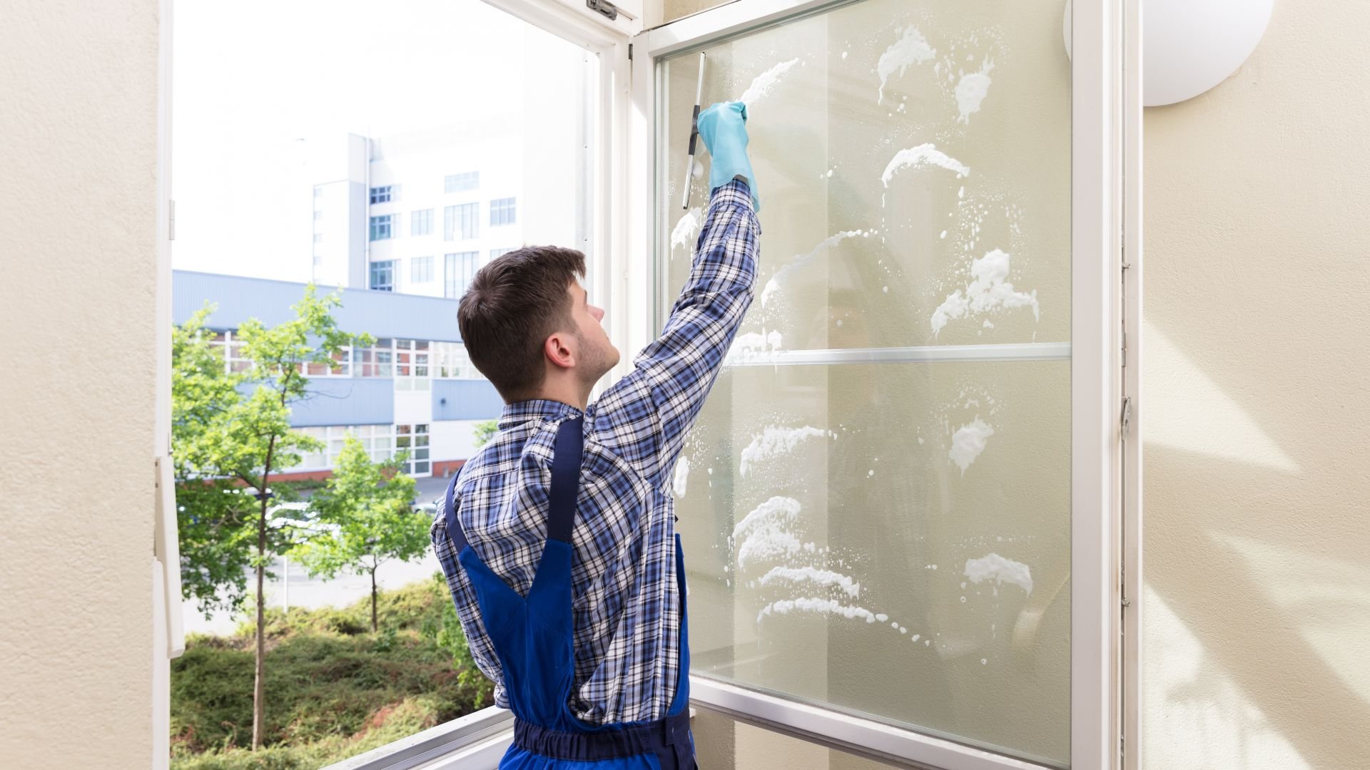 Person cleaning windows with spray and cloth in an office building